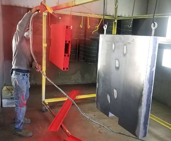 men applying powder coating to metal pieces